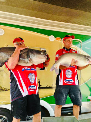 two men holding catfish