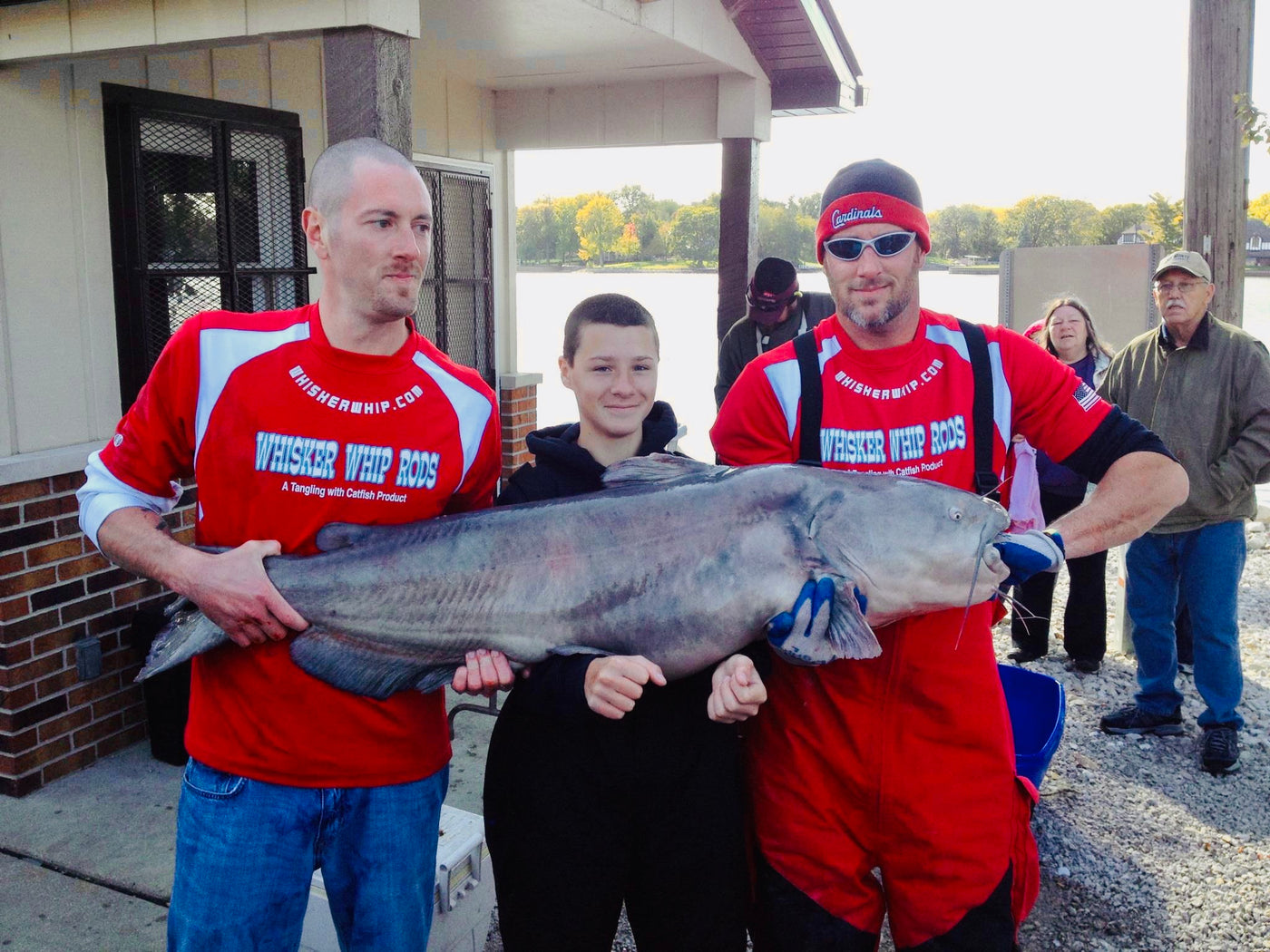two men and young boy holding a giant catfish