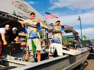 two men each holding a large catfish